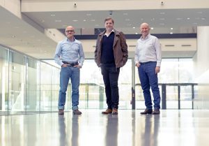 picture of three middle-aged men standing up in a room