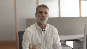 Picture of a men. Grey hair and beard and wearing a white shirt.